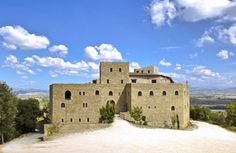 an old castle sits on top of a hill with trees and clouds in the background