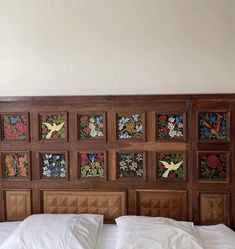 a bed with white sheets and decorative wooden headboard