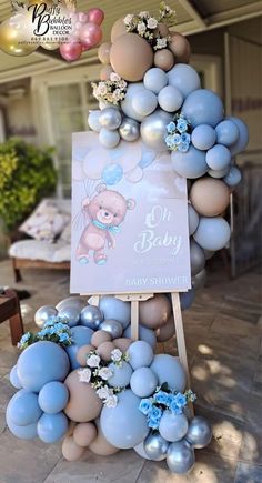 a baby shower sign surrounded by balloons and flowers