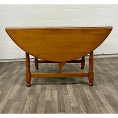 a wooden table sitting on top of a hard wood floor next to a white wall