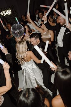 a group of people that are standing in front of each other at a party with confetti sticks