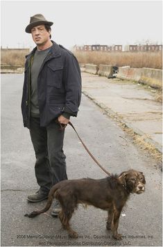 a man standing next to a brown dog on a leash