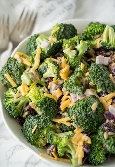 a white bowl filled with broccoli and cheese on top of a marble table