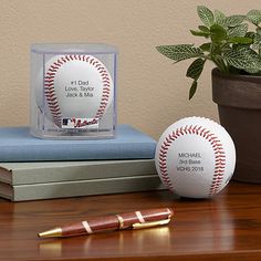 two baseballs and a pen sitting on top of a wooden table next to a potted plant