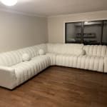 a large white couch sitting on top of a hard wood floor next to a window