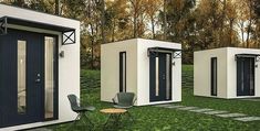 three white portable homes sitting on top of a grass covered field next to a small table and chair