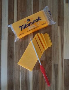 there is a piece of cheese next to a knife on the table and a package of cheese