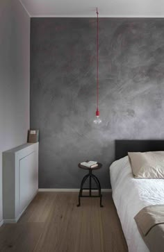 a bed sitting in a bedroom next to a wall with a red light hanging from it