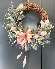 a wreath with flowers and eggs hanging on a door