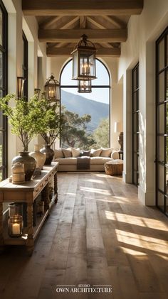 the inside of a house with wood flooring and large windows, lanterns hanging from the ceiling