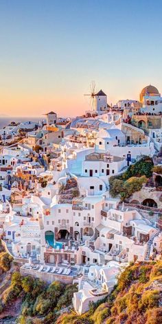 an aerial view of the white village of oia, with windmills in the background