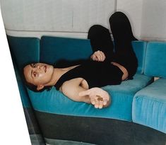 a woman laying on top of a blue couch