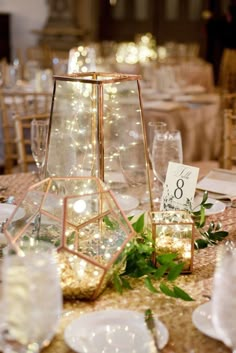 the table is set up for a wedding reception with gold linens and greenery