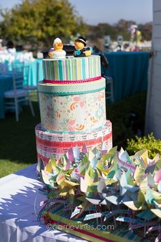 a multi layer cake sitting on top of a table covered in paper flowers and birds