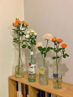 three vases filled with flowers sitting on top of a book shelf