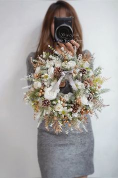 a woman holding a camera taking a photo with a wreath on her chest and the words merry christmas written across it