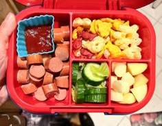 a person holding a red tray filled with different types of vegetables and meats in it