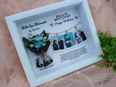 a photo frame with flowers and pictures hanging on a clothes line next to a plant