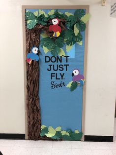 a door decorated to look like a tree with parrots on it and the words don't just fly souv