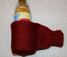 a red knitted arm warmer with a bottle in the middle on a white surface