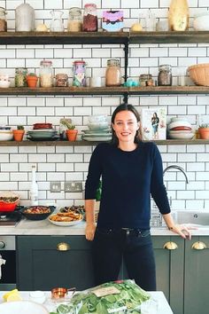 a woman standing in front of a kitchen counter with lots of food on top of it