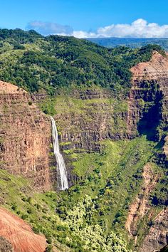 a large waterfall in the middle of a lush green valley