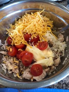 a metal bowl filled with rice, tomatoes and cheese