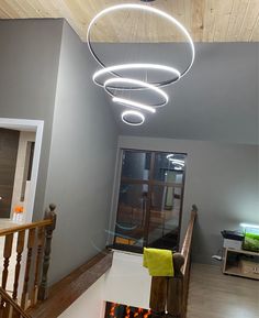 a light fixture hanging from the ceiling in a room with wood floors and stairs,