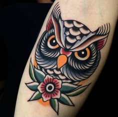 an owl tattoo on the arm with flowers