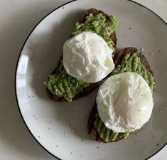 two pieces of bread with avocado and poached eggs on them sitting on a plate