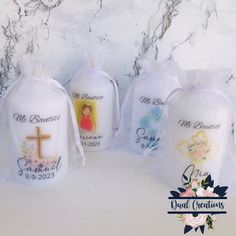 three personalized candles in organ bags with the names of each candle and cross on them