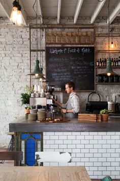 a man is behind the bar in a restaurant with brick walls and exposed ceilinging