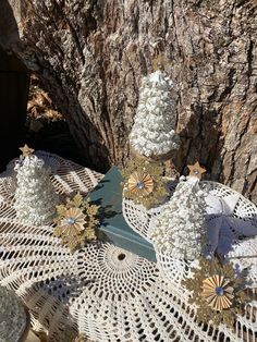 a table topped with white doily covered in gold and silver decorations next to a tree