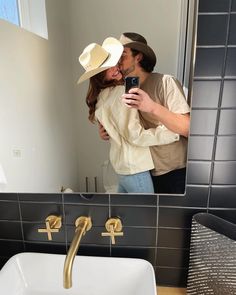 a man and woman kissing in front of a bathroom mirror while taking a selfie