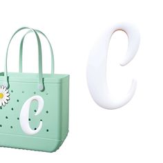 a green bag with a flower on it next to the letter c and a white plastic object