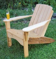 a wooden chair sitting in the grass next to a glass of orange juice on top of it