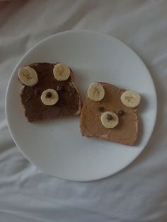 two pieces of bread with peanut butter and banana slices on them sitting on a white plate