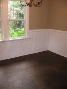 an empty room with a chandelier hanging from the ceiling and two windows in it