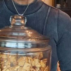 a man holding a large glass jar filled with nuts and other things in front of him