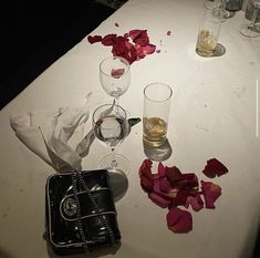 the table is covered with rose petals and empty wine glasses, napkins, and an old purse