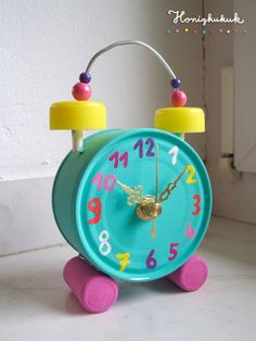 a blue clock with numbers on it sitting on the floor in front of a white wall