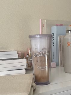 a coffee cup sitting on top of a white desk next to books and other items