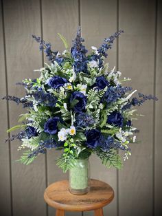 a vase filled with blue and white flowers on top of a wooden table next to a wall