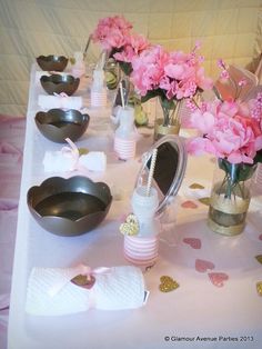 the table is set up with pink flowers and silver dishes, napkins and utensils