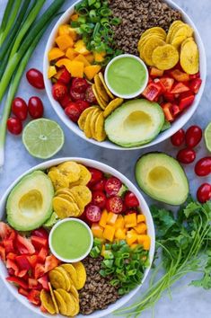 two white bowls filled with different types of vegetables and fruits next to some green onions