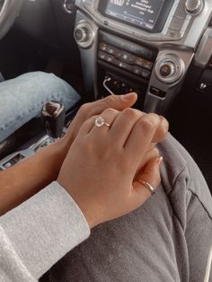 a woman is holding the hand of her husband while he sits in their car with his steering wheel behind him