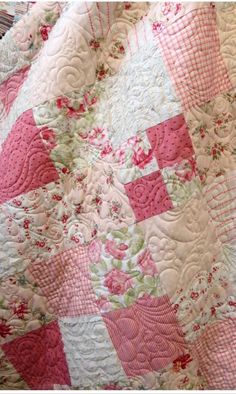 a pink and white quilt with flowers on it