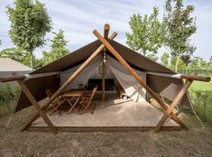 a tent set up in the middle of a field with tables and chairs around it