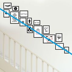 a stair case with pictures on the wall and blue tape going up it's handrail