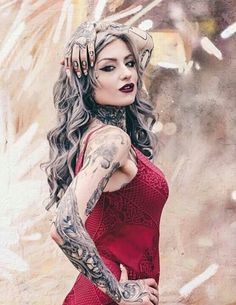 a woman in a red dress with tattoos on her arm and arms, posing for the camera